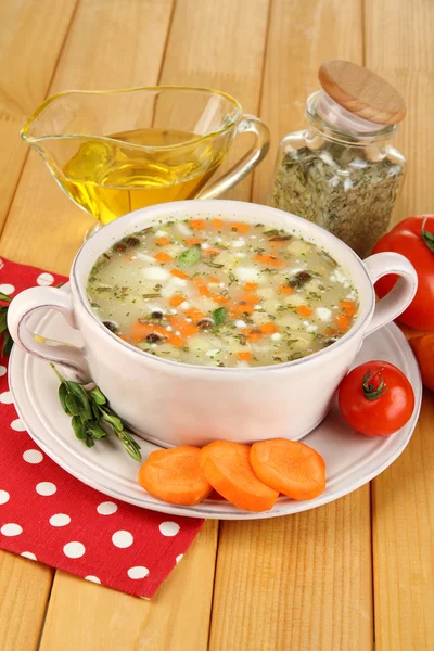 Nourishing soup in pink pan on wooden table close-up — Stock Photo, Image