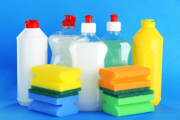 Bottles of dishwashing liquid and sponges on color background — Stock Photo, Image