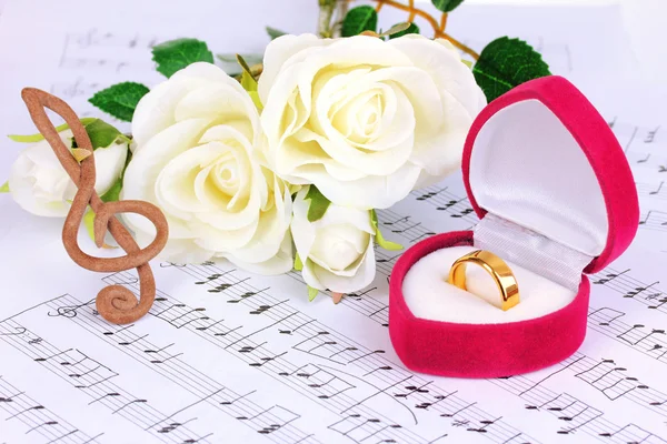 Fenda aguda, rosas e caixa segurando anel de casamento no fundo musical — Fotografia de Stock