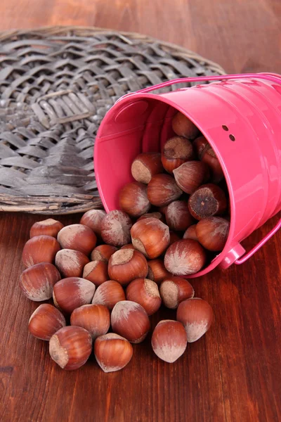 Overturned bucket with hazelnuts on wooden background — Stock Photo, Image