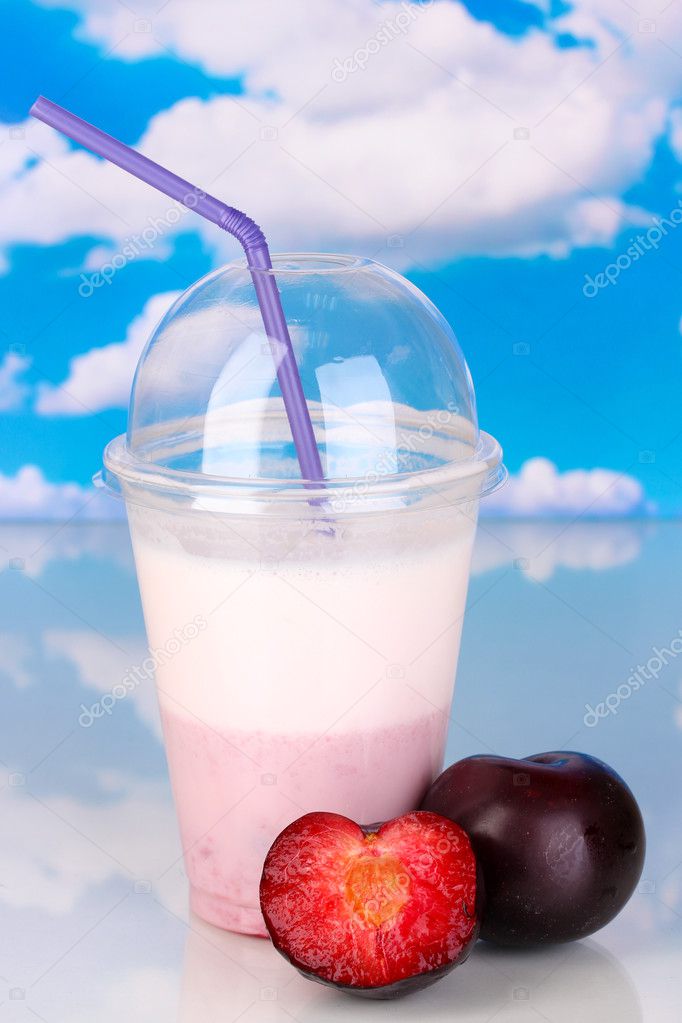 Delicious milk shake with fruit on table on sky background