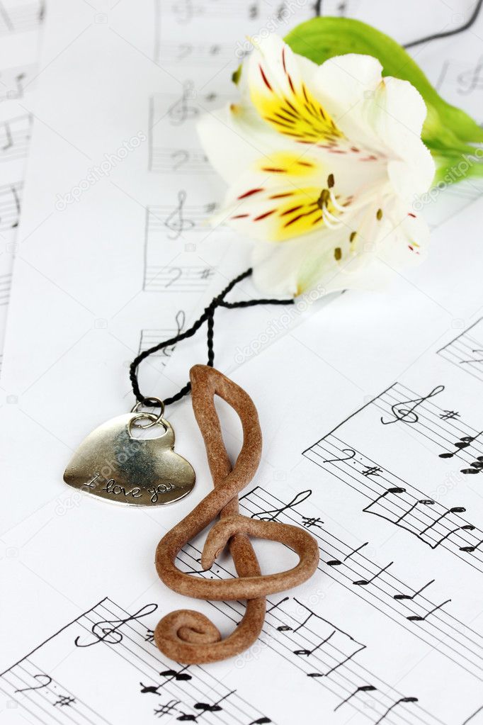Treble clef, pendant and flower on musical background