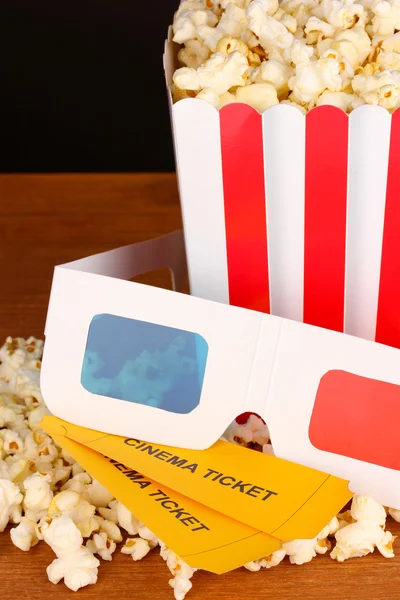 Popcorn mit Eintrittskarten und Kinogläsern auf Holztisch auf braunem Hintergrund — Stockfoto