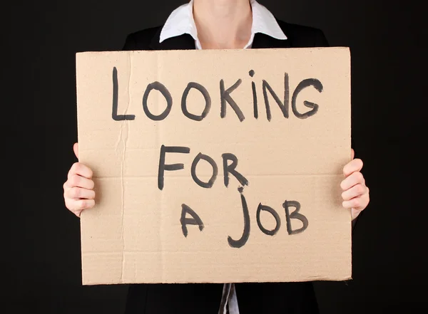 Imprenditrice che tiene il cartello "Alla ricerca di un lavoro", isolata su nero — Foto Stock