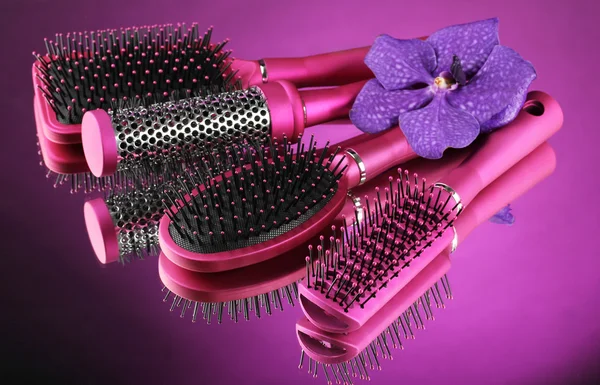 Comb brushes and flower on purple background — Stock Photo, Image