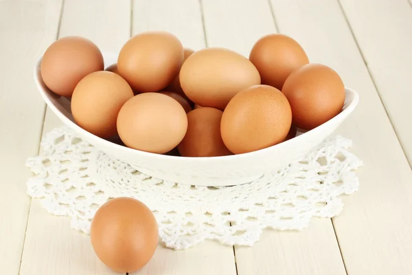 Huevos en tazón blanco sobre mesa de madera de cerca — Foto de Stock