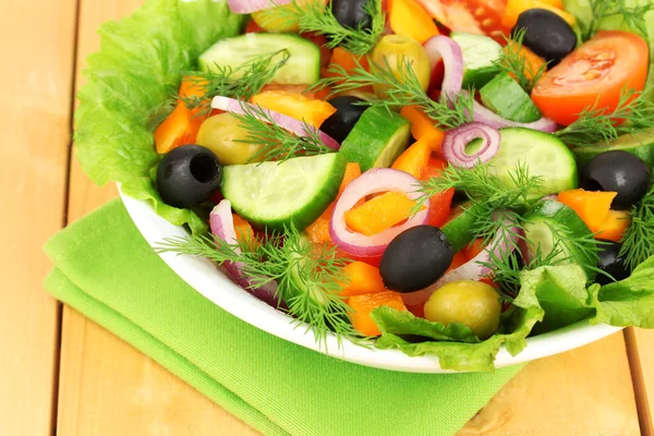 Frischer Salat im Teller auf Holztisch — Stockfoto