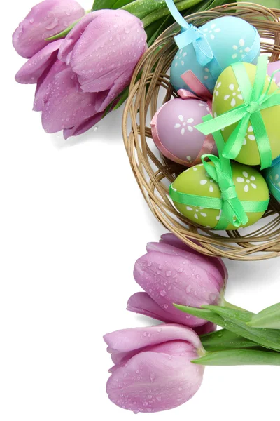 Luminose uova di Pasqua in cesto e tulipani, isolate su bianco — Foto Stock
