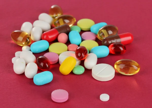 Assortment of pills, tablets and capsules on red background — Stock Photo, Image