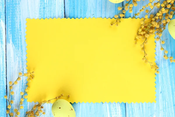 Tarjeta vacía con huevos de Pascua y flores de mimosa, sobre fondo de madera azul —  Fotos de Stock