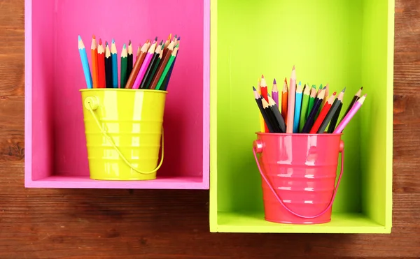 Colorful pencils in pails on shelves on wooden background — Stock Photo, Image