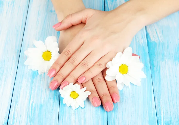 Frau Hände mit rosa Maniküre und Blumen, auf farbigem Hintergrund — Stockfoto