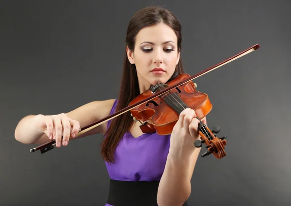 Hermosa joven con violín sobre fondo gris — Foto de Stock