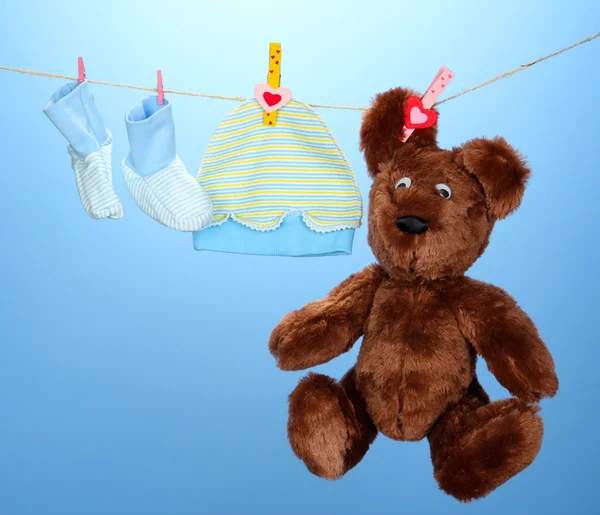 Dětské oblečení na prádelní šňůru, na modrém pozadí — Stock fotografie