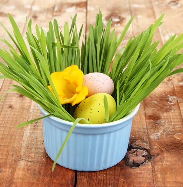 Easter eggs in bowl with grass on wooden table close up — Stockfoto