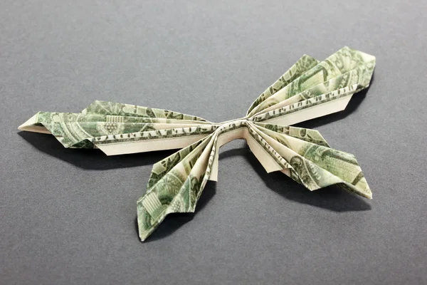 Доллар складывается в бабочку на сером фоне — стоковое фото