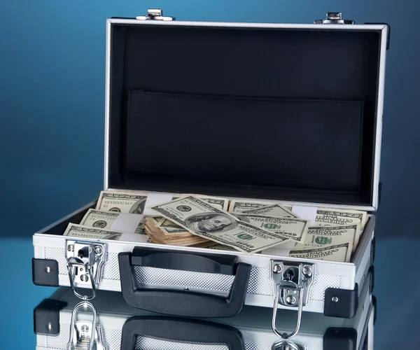 Koffer met 100 dollarbiljetten op blauwe achtergrond — Stockfoto