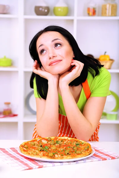 Домохозяйка с вкусной пиццей на фоне кухни — стоковое фото