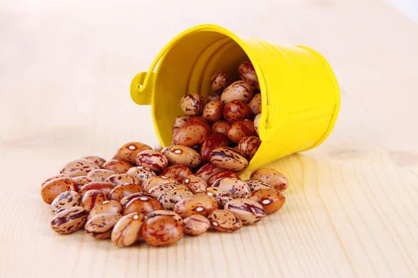 Overturned bucket with beans on wooden background — Stock Photo, Image