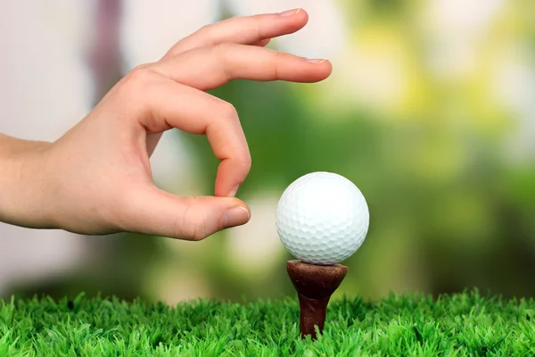 Mão empurrando bola de golfe na grama verde ao ar livre perto — Fotografia de Stock