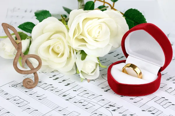 Treble clef, rozen en vak bedrijf trouwring op muzikale achtergrond — Stockfoto