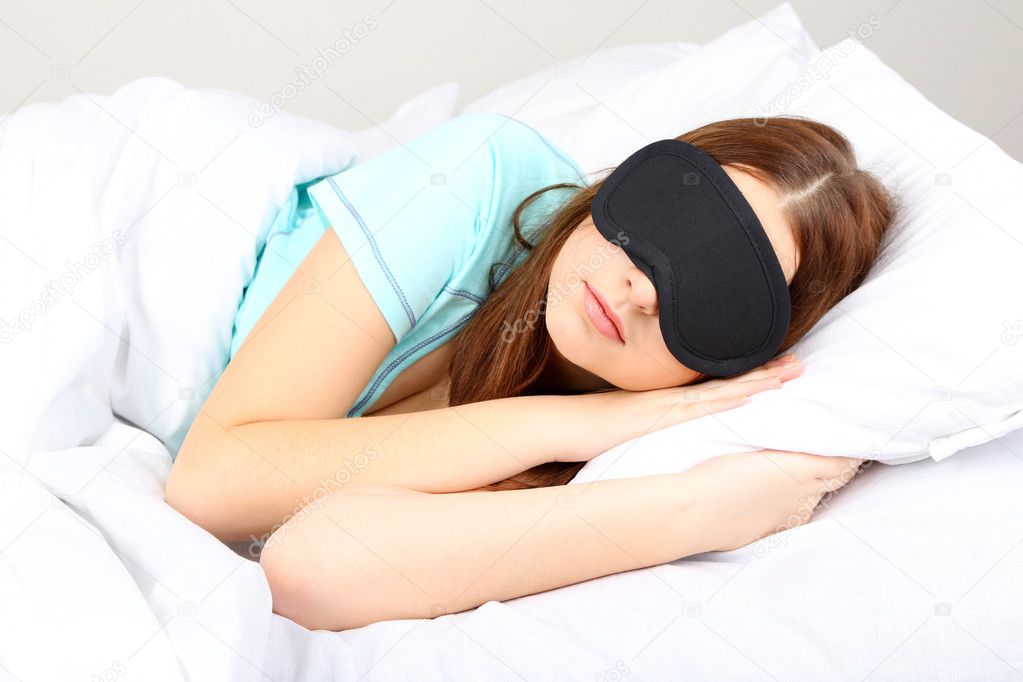 Beautiful young woman sleeping in bed with eye mask