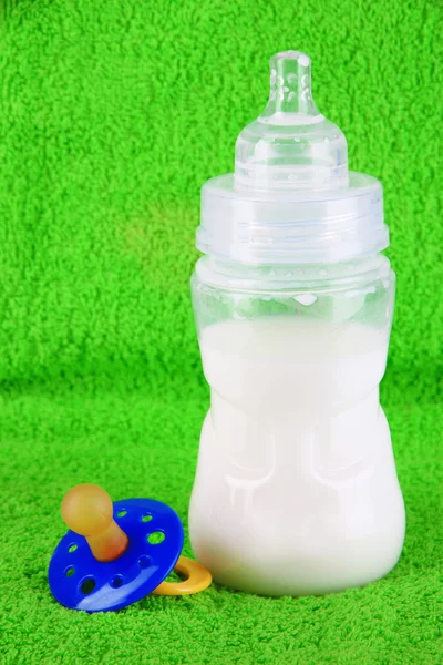 Бутылка для молока и соска на фоне полотенца — стоковое фото
