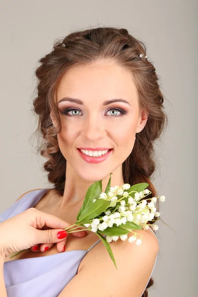 Mladá žena s krásný účes a květiny, na šedém pozadí — Stock fotografie