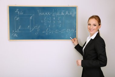 Portrait of teacher woman writing on the chalkboard in classroom clipart
