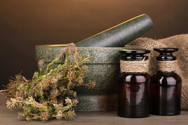 Трава тимьяна и раствор на деревянном столе на коричневом фоне — стоковое фото