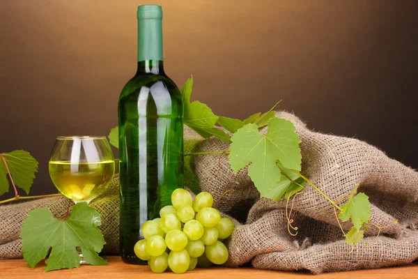 Bottiglia di grande vino con vetro su tavolo di legno su sfondo marrone — Foto Stock