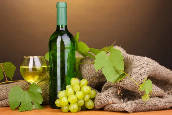 Botella de gran vino con copa sobre mesa de madera sobre fondo marrón — Foto de Stock