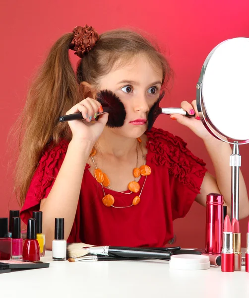 Liten flicka i sin mors klänning med make up penslar — Stockfoto