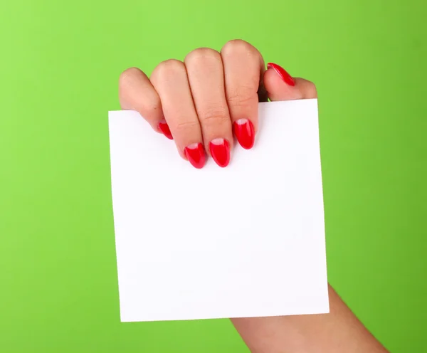 Mano della donna che tiene carta bianca su sfondo a colori — Foto Stock