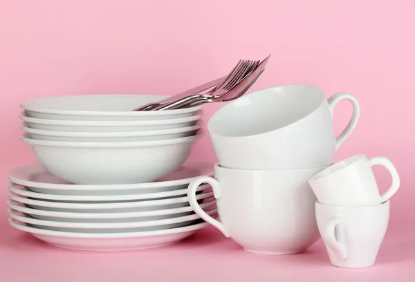 Čisté bílé nádobí na růžovém pozadí — Stock fotografie