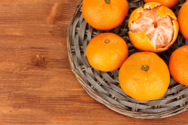 Smakelijke mandarijnen op rieten mat op houten achtergrond — Stockfoto