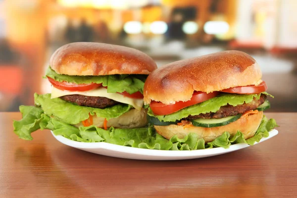 Kafede masada plaka üzerinde büyük ve lezzetli hamburger — Stok fotoğraf