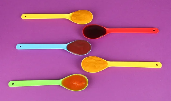 Baby puree in spoons on purple background — Stock Photo, Image