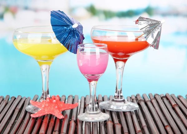 Glasses of cocktails on table near pool — Stock Photo, Image