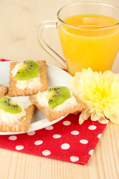 Gustose tartine con formaggio e kiwi, su piatto di colore, su fondo di legno — Foto Stock