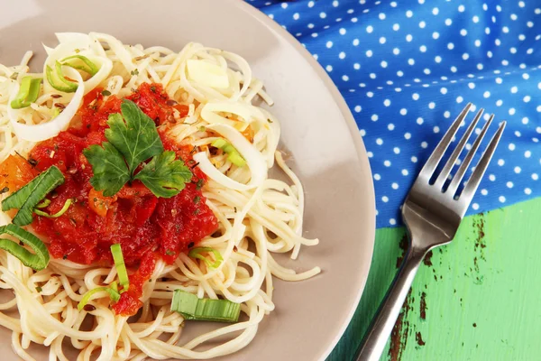 Välsmakande spaghetti med sås och grönsaker på tallriken på träbord närbild — Stockfoto