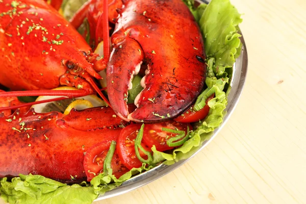 Червоний омари на тарілці з овочами на дерев'яному столі крупним планом — стокове фото