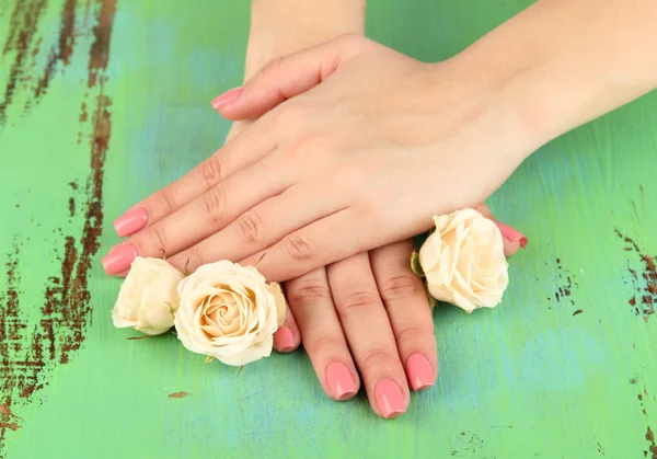Mains de femme avec manucure rose et fleurs, sur fond de couleur — Photo