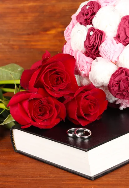 Anillos de boda en la biblia con rosas sobre fondo de madera — Foto de Stock