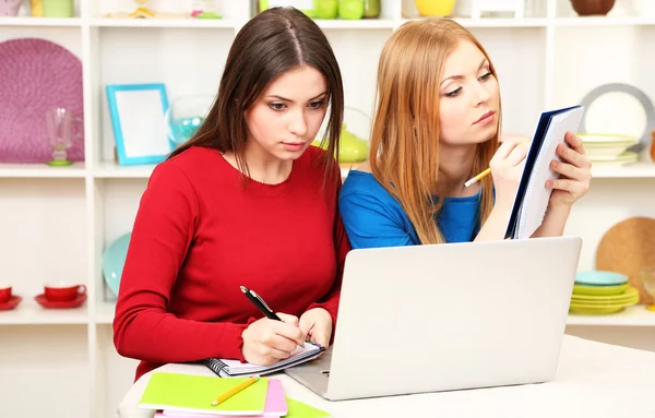 Twee meisje vrienden praten en studeren in keuken — Stockfoto