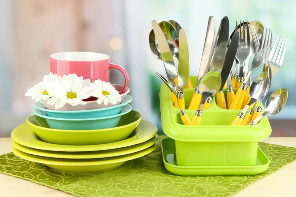 Placas, garfos, facas, colheres e outros utensílios de cozinha em guardanapo de cor, no fundo brilhante — Fotografia de Stock