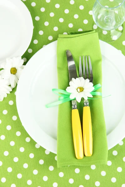 Knife and fork wrapped in napkin, on plate, on color tablecloth background — Stock Photo, Image