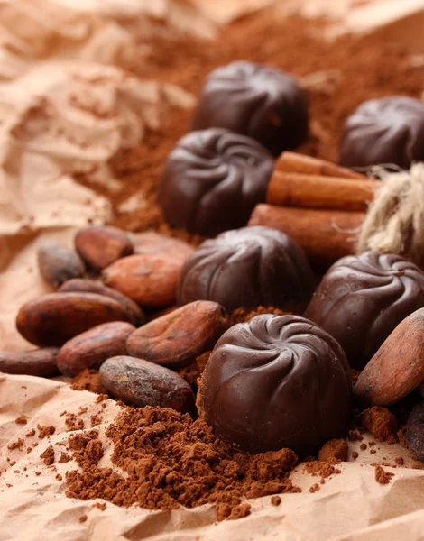 Composition of chocolate sweets, cocoa and spices on brown background — Stock Photo, Image