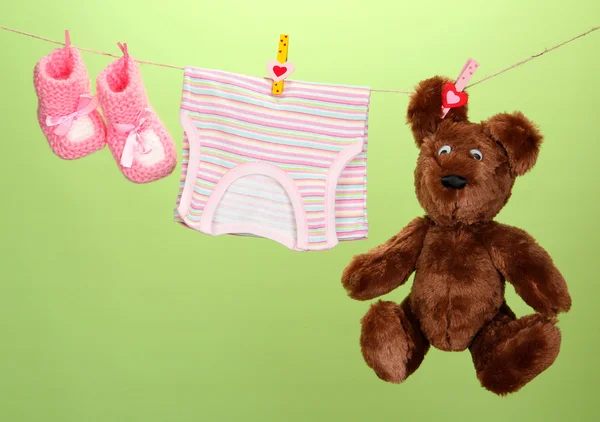 Baby clothes hanging on clothesline, on color background — Stock Photo, Image