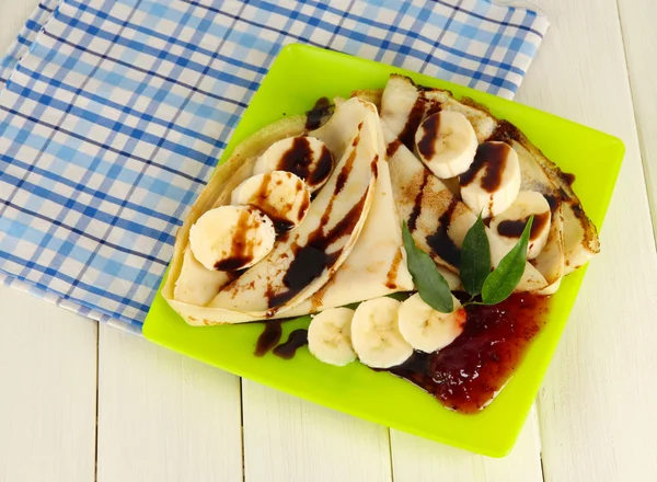 Pancakes with banana on plate on wooden background — Stock Photo, Image